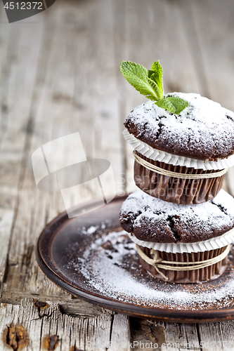 Image of Fresh dark chocolate muffins with sugar powder and mint leaf on 