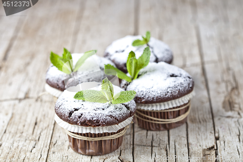 Image of Fresh chocolate dark muffins with sugar powder and mint leaf on 