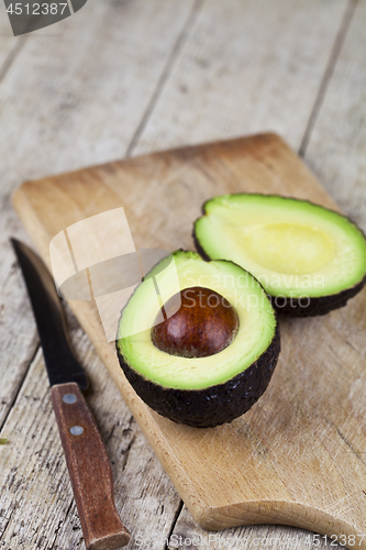 Image of Avocado and knife on cutting board on old wooden table backgroun