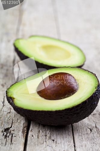 Image of Fresh organic avocado halves on old wooden table background. Fre