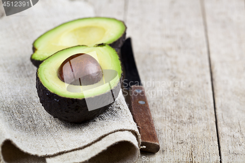 Image of Avocado and knife on linen napkin old wooden table background. F