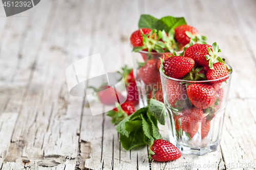 Image of Red fresh strawberries in two glasses and mint leaves on rustic 