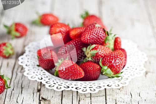 Image of Fresh red strawberries on white plate on rustic wooden backgroun