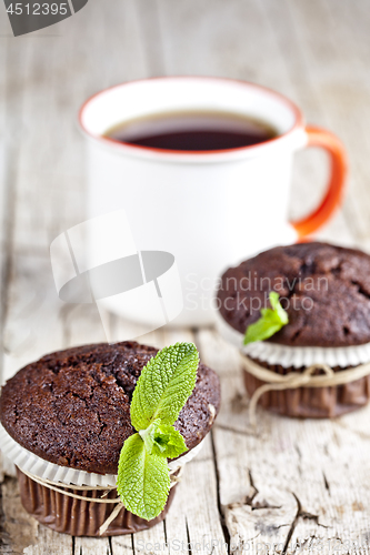 Image of Fresh dark chocolate muffins with mint leaves and cup of tea on 
