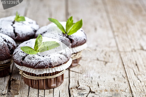 Image of Fresh chocolate dark muffins with sugar powder and mint leaf on 