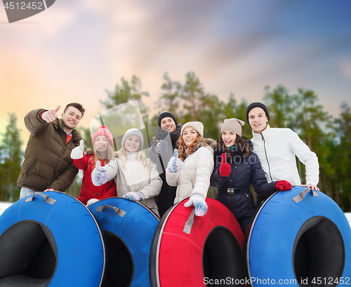 Image of happy friends with snow tubes outdoors in winter