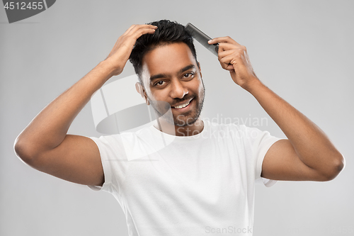 Image of happy indian man brushing hair with comb