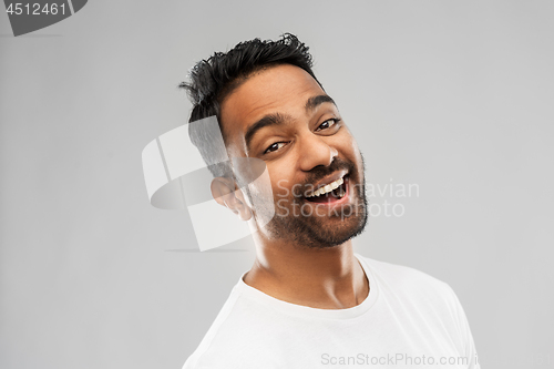 Image of young laughing indian man over gray background