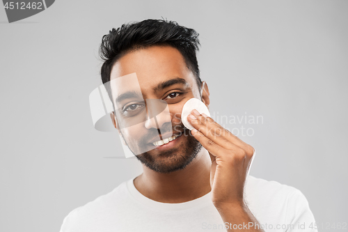 Image of smiling indian man cleaning face with cotton pad