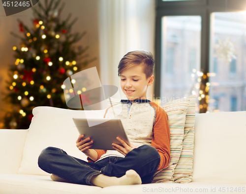 Image of boy with tablet computer on christmas at home
