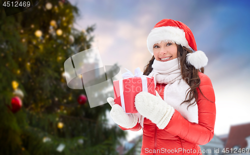 Image of happy woman with gift over christmas tree