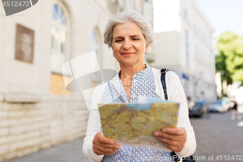 Image of senior woman or tourist with map on city street