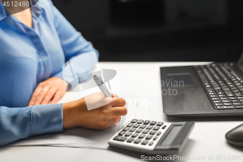 Image of businesswoman with papers working at night office