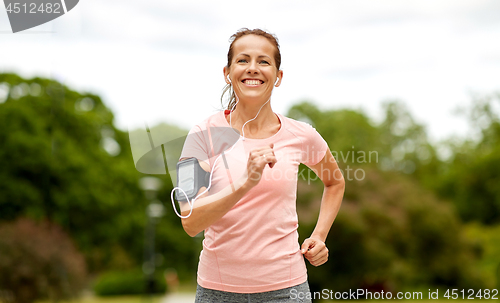 Image of woman with earphones add armband jogging at park