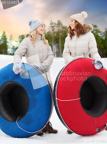 Image of happy teenage girls with snow tubes in winter