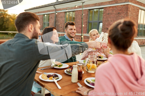 Image of happy friends toasting drinks at rooftop party