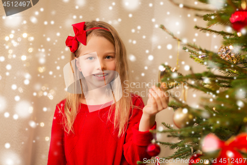 Image of happy girl in red decorating christmas tree