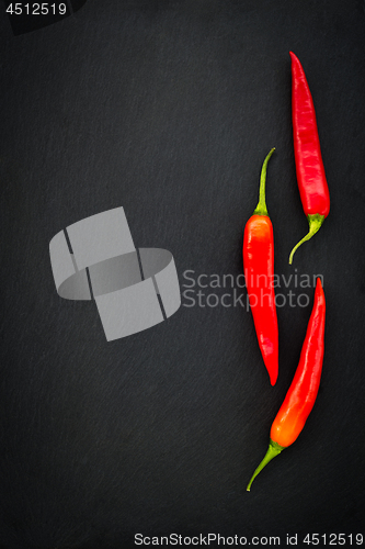 Image of Three red chili peppers on dark background