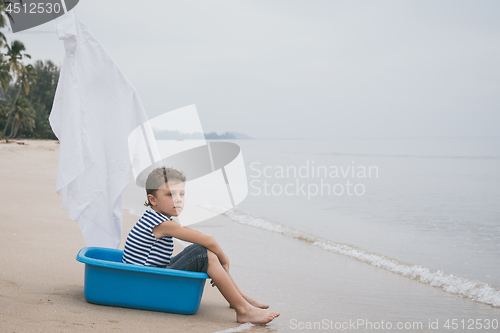 Image of One happy little boy playing on the beach at the day time.