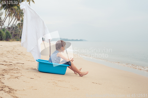 Image of One happy little boy playing on the beach at the day time.