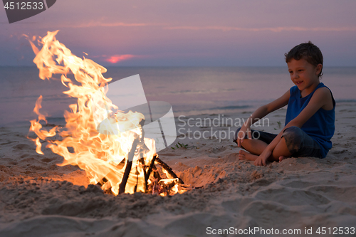 Image of One happy little boy playing on the beach at the sunset time.