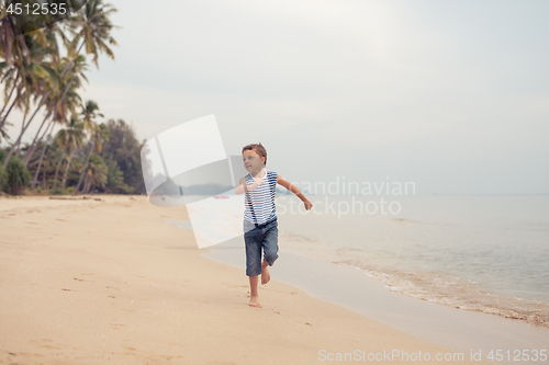 Image of One happy little boy playing on the beach at the day time.