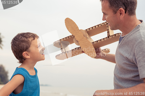 Image of Father and son playing with cardboard toy airplane