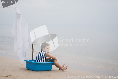 Image of One little boy playing on the beach at the day time.