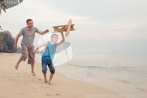 Image of Father and son playing with cardboard toy airplane