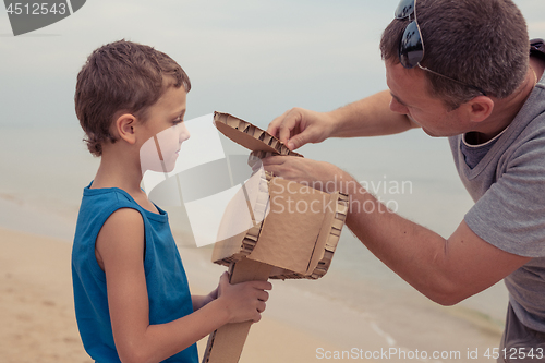 Image of Father and son playing with cardboard toy airplane