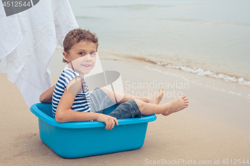 Image of One happy little boy playing on the beach at the day time.