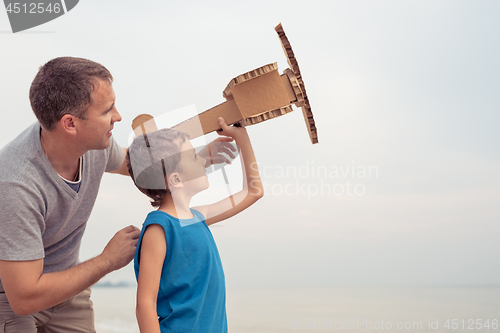 Image of Father and son playing with cardboard toy airplane