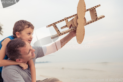 Image of Father and son playing with cardboard toy airplane