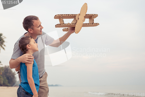 Image of Father and son playing with cardboard toy airplane