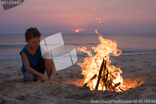 Image of One happy little boy playing on the beach at the sunset time.