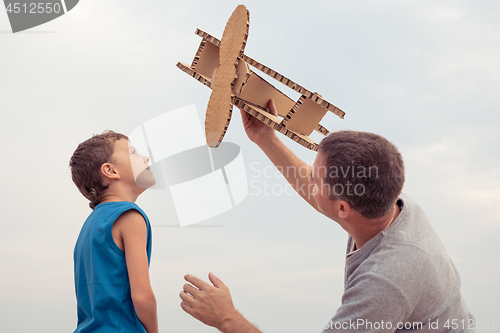 Image of Father and son playing with cardboard toy airplane