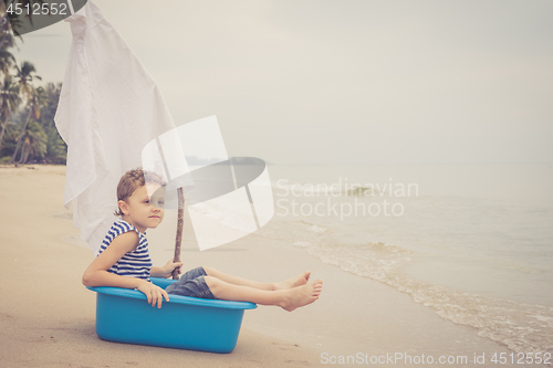 Image of One happy little boy playing on the beach at the day time.