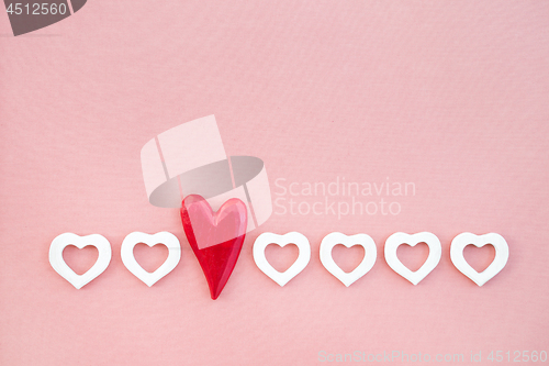Image of Row of red and white wooden hearts on pink background