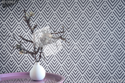 Image of Mossy twigs in a vase on geometric wallpaper background