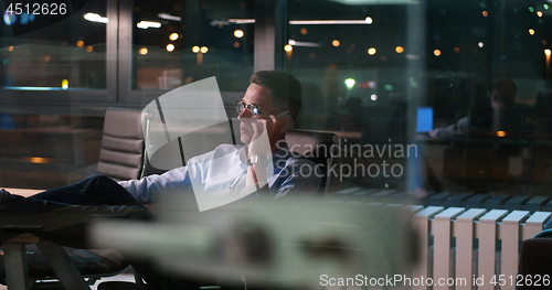 Image of businessman sitting with legs on desk at office