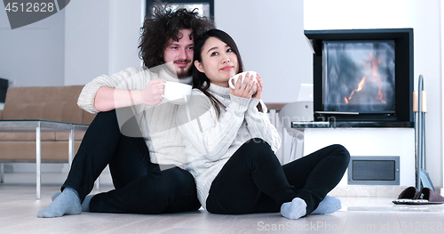 Image of multiethnic romantic couple  in front of fireplace