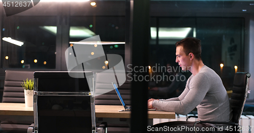 Image of man working on laptop in dark office