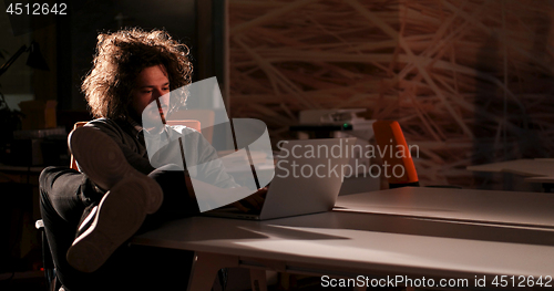 Image of businessman sitting with legs on desk at office