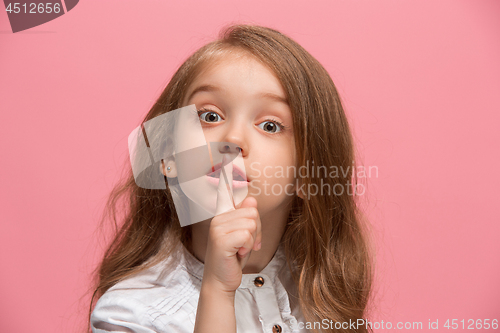 Image of The young teen girl whispering a secret behind her hand over pink background