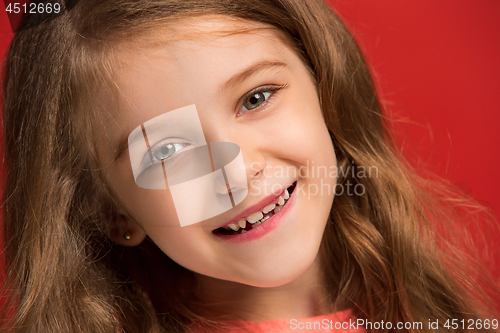 Image of The happy teen girl standing and smiling against red background.