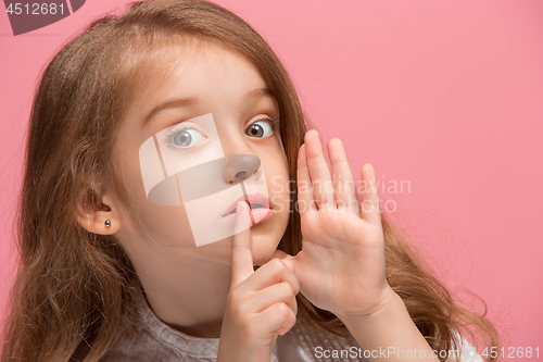 Image of The young teen girl whispering a secret behind her hand over pink background