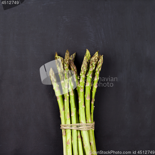 Image of Bunch of fresh raw garden asparagus on black board background.