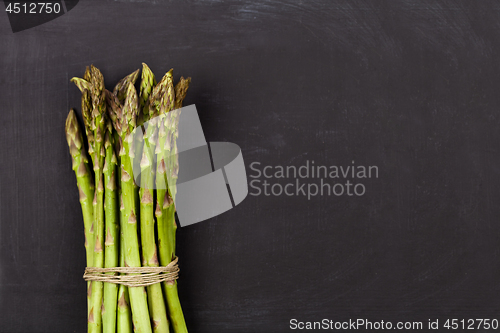 Image of Bunch of fresh raw garden asparagus on black board background.