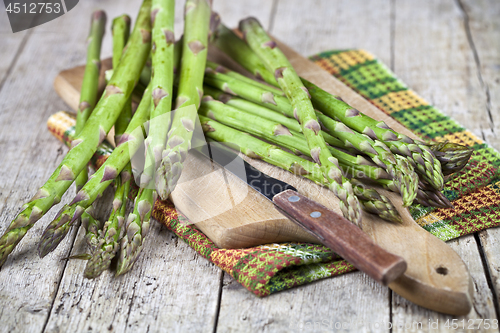 Image of Fresh raw garden asparagus and knife closeup on cutting board on