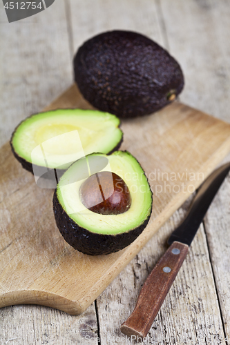 Image of Avocado and knife on cutting board on old wooden table backgroun